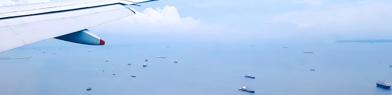 Airplane wing over an ocean full of ships
