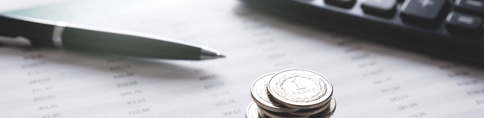 a pen, a calculator, a stack of coins on a financial sheet